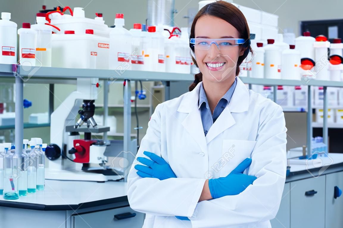 Retrato de un químico sonriendo con los brazos cruzados en el laboratorio