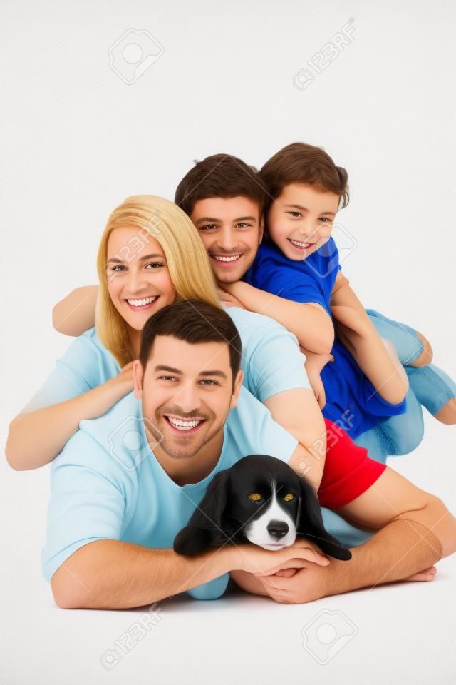 白い背景の上の犬と互いの上に横たわっている幸せな家族の肖像画