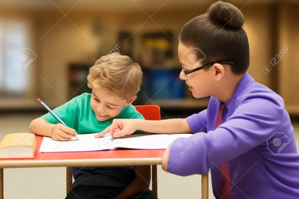 Porträt der Lehrerin helfen kleiner Junge mit Hausaufgaben im Klassenzimmer