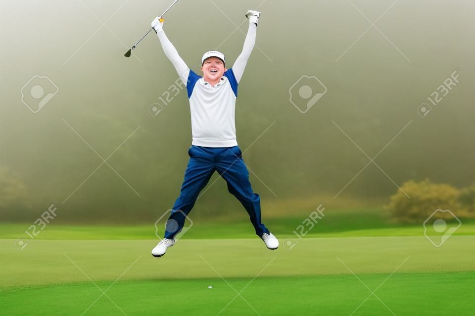 Podekscytowany zawodnik skacze w górę i uśmiecha się w aparacie w mglisty dzień na polu golfowym