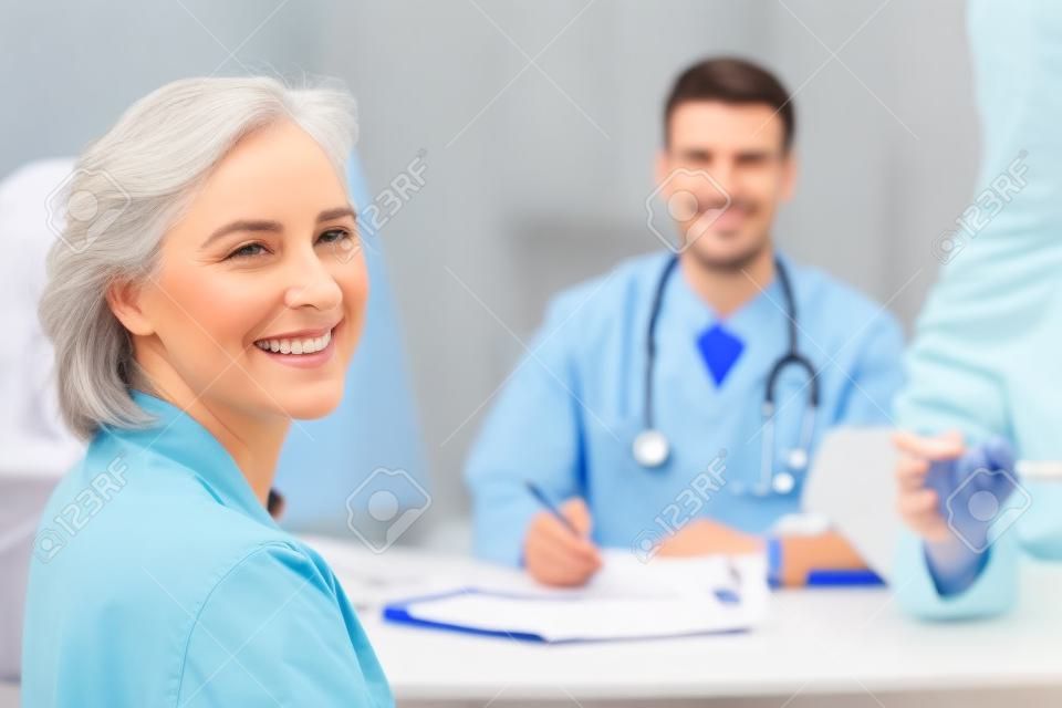Paciente e médico que sorriem na câmera no escritório médico