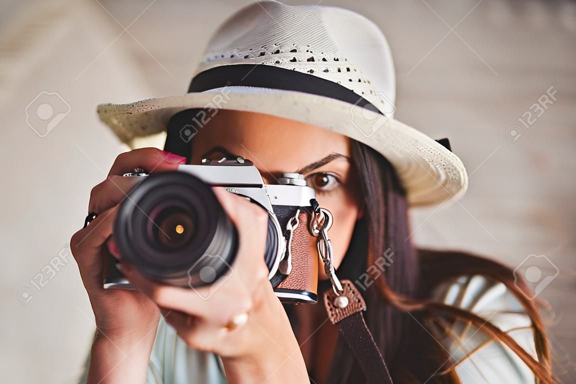 Jolie hipster en utilisant son appareil photo vintage sur fond de planches de bois
