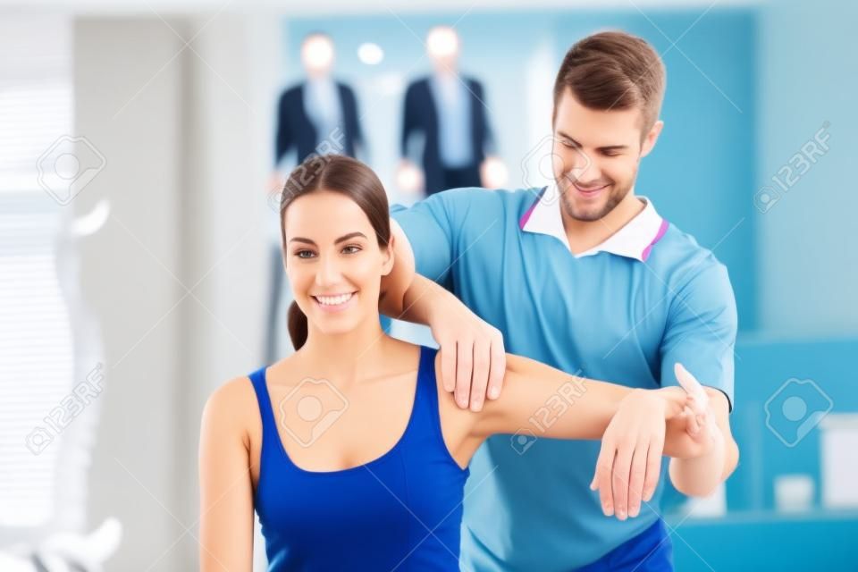 Medico allungando una giovane donna braccio in studio medico