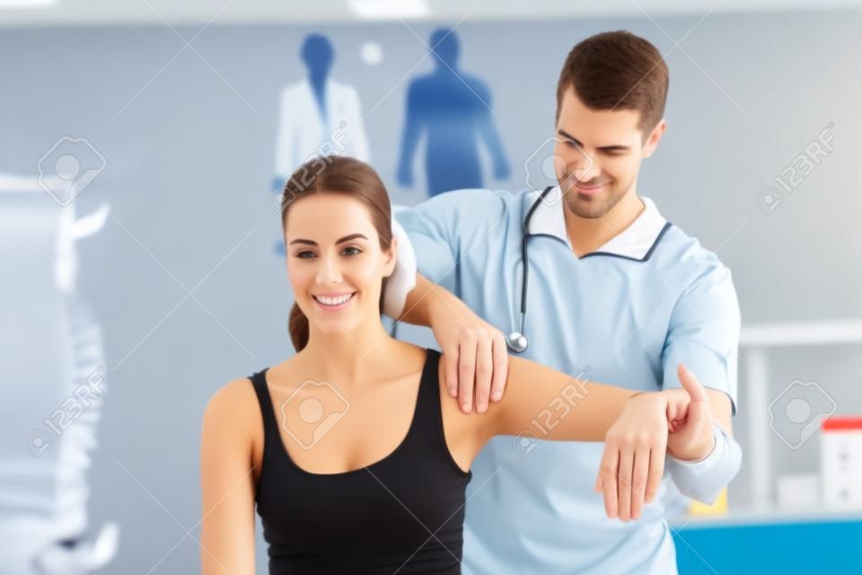 Medico allungando una giovane donna braccio in studio medico