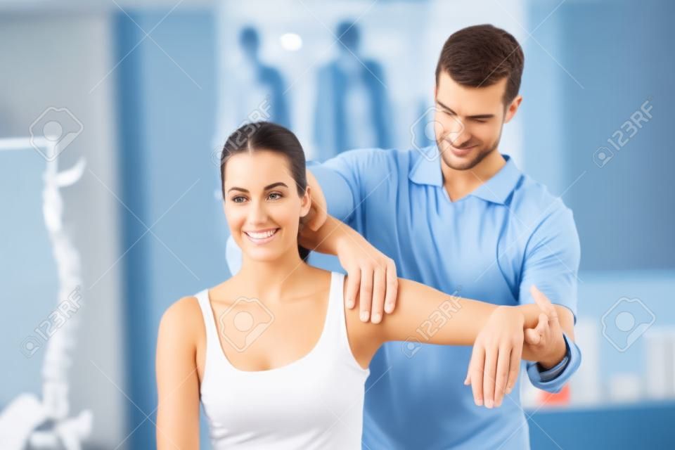 Docteur étirer un bras de jeune femme dans le bureau médical