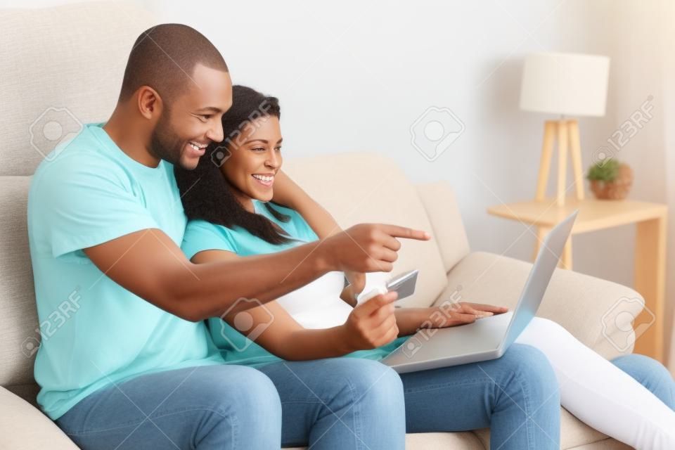 Coppie che godono di shopping online, seduto sul divano a casa