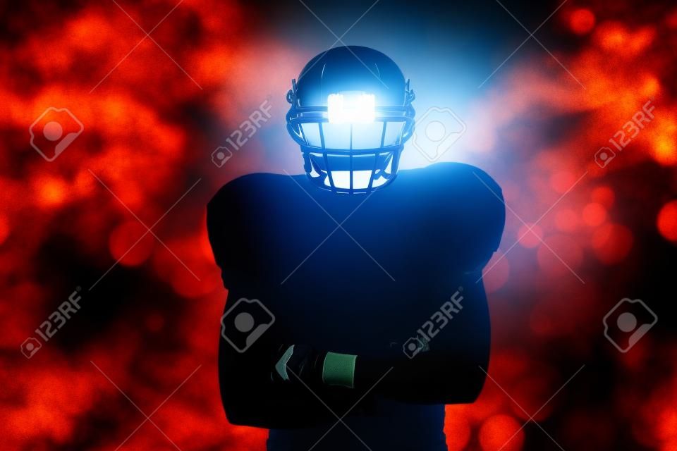 Silhouette American football player standing against glowing background