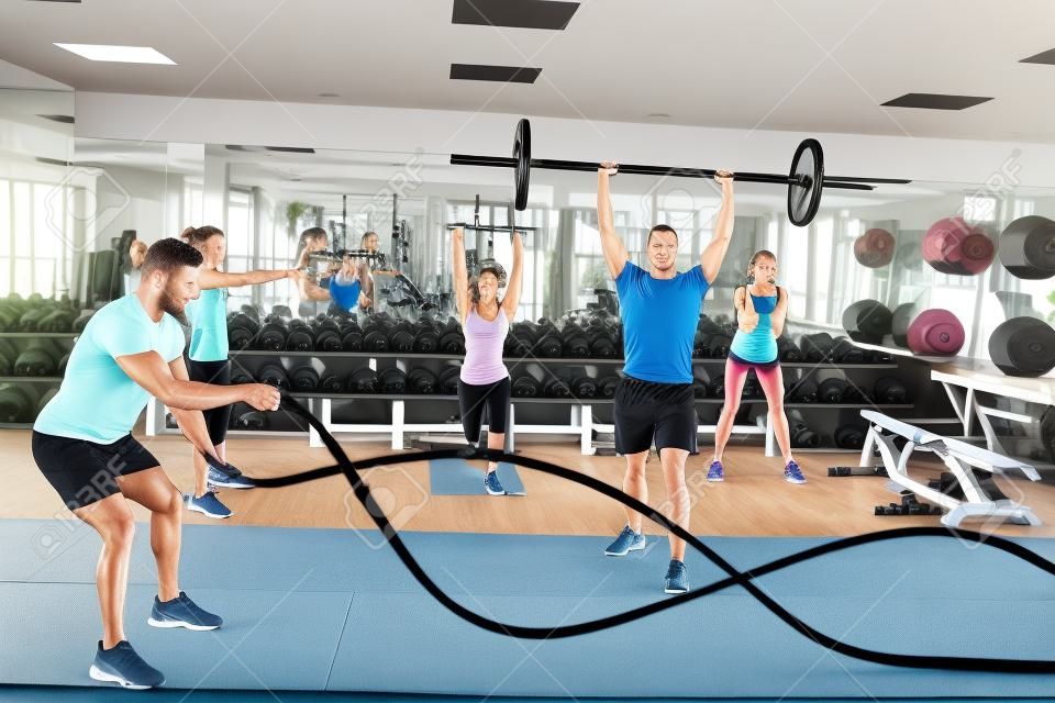 Las personas en forma de trabajo a cabo en la sala de pesas en el gimnasio