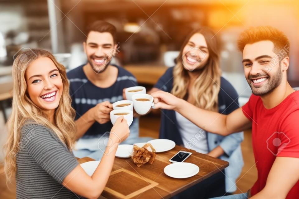 Sonrientes amigos disfrutando de café juntos en la cafetería