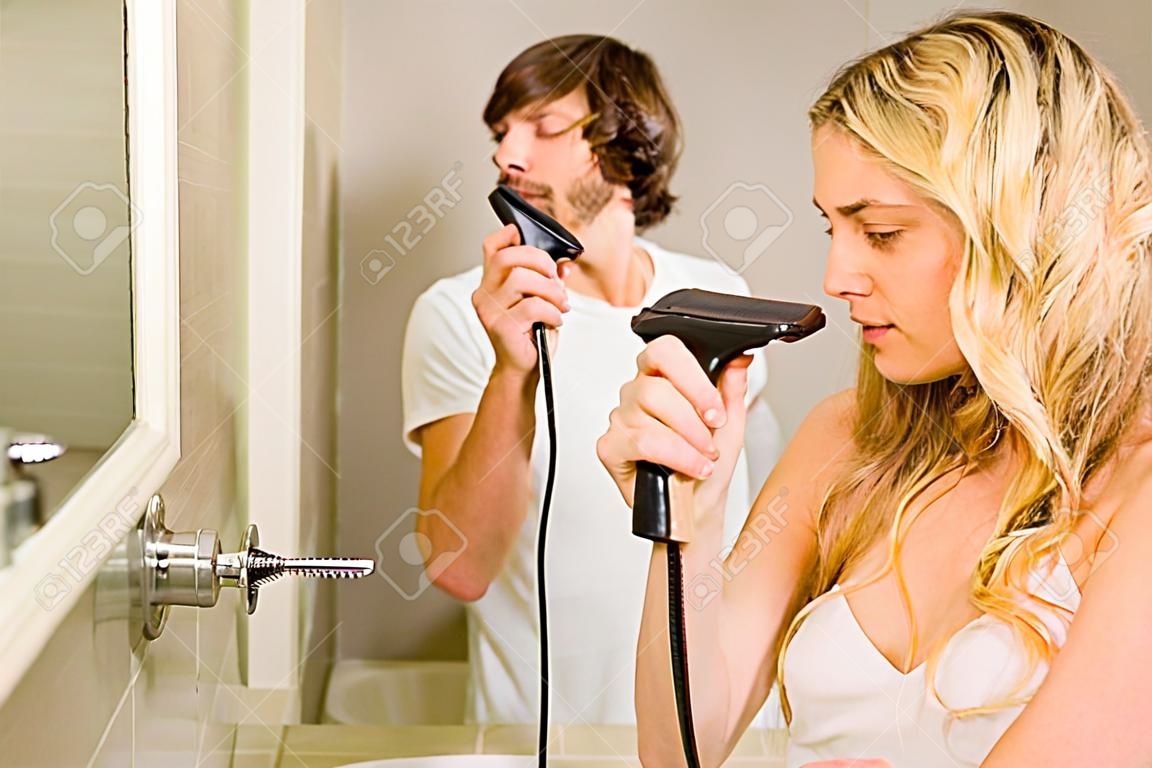 Cute couple using a razor and a straightener in the bathroom at home