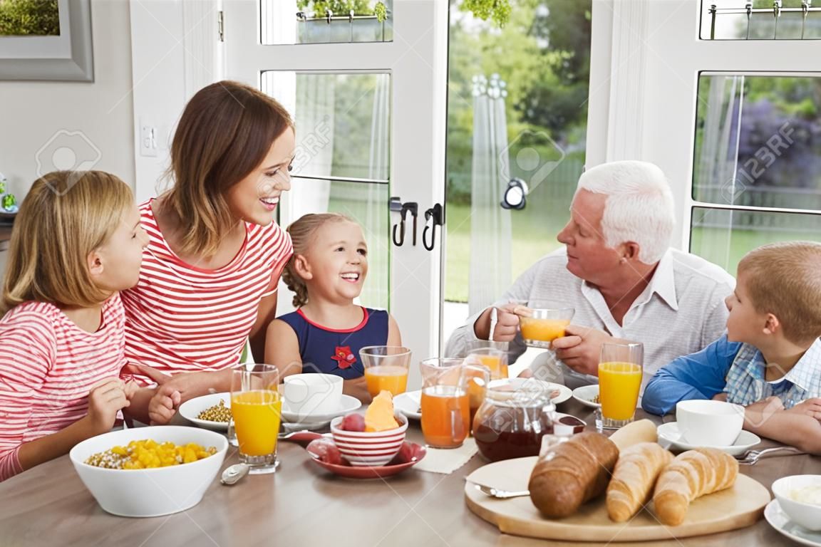 Felice famiglia multi-generazione che ha la prima colazione a casa