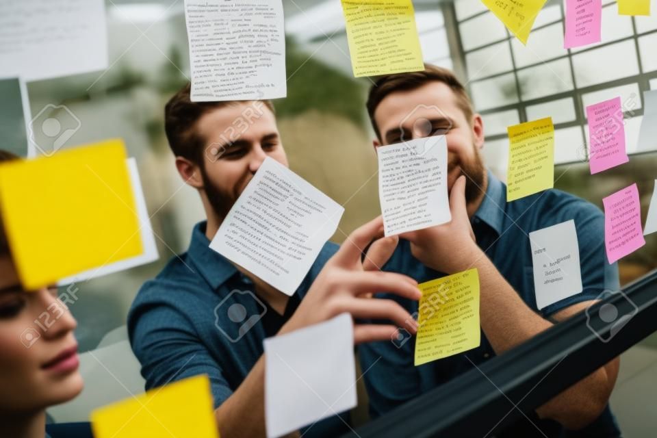 Hipsters Lesen eines Post-it auf einem Fenster im Büro