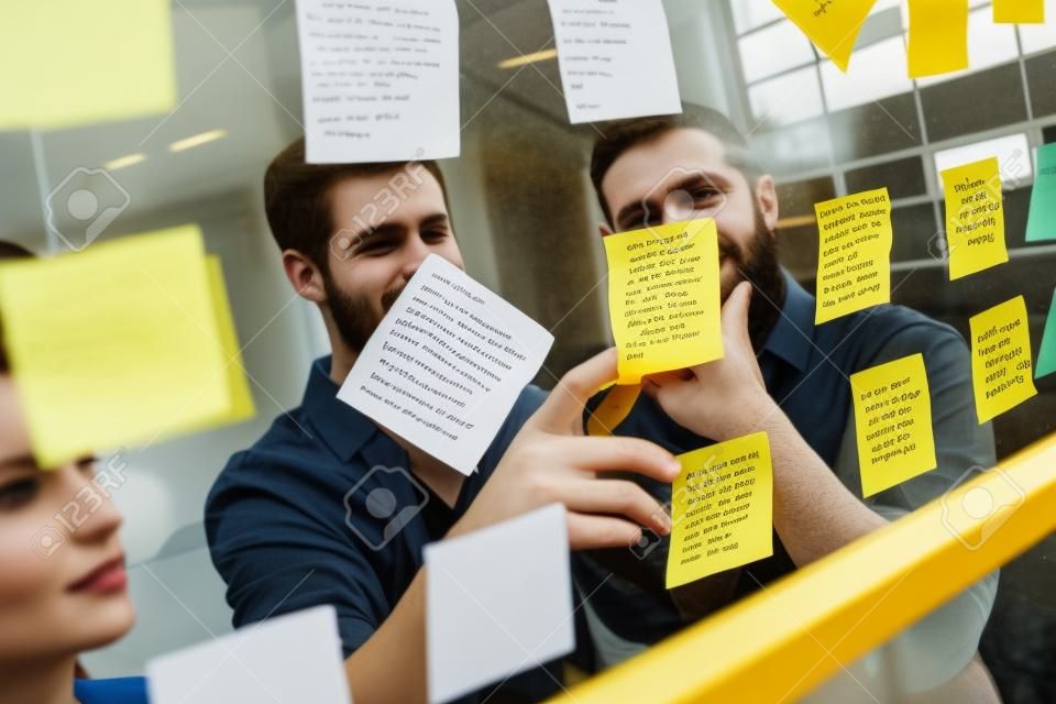 Hipsters reading a post it on a window in the office