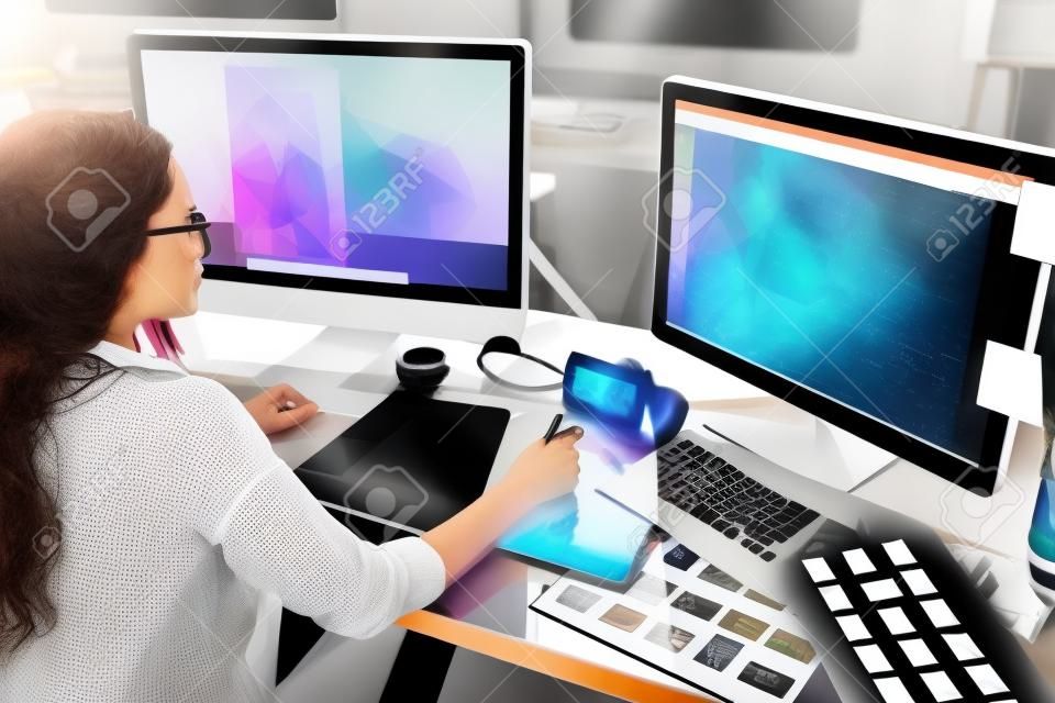Female graphic designer using graphic tablet while working on computer at office