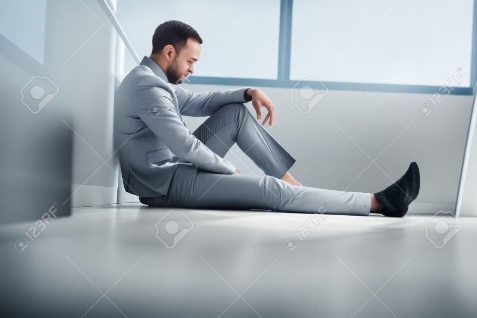 exécutif sad assis sur le sol dans le bureau
