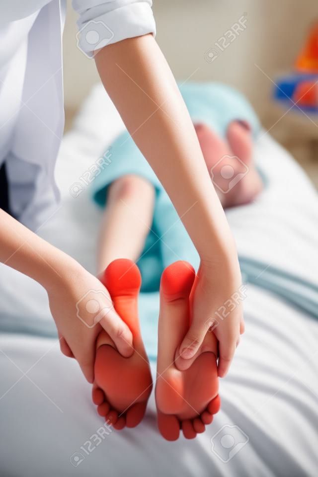 Ragazzo che si trova sul letto mentre ricevendo massaggio del piede dal giovane terapista femminile al reparto di ospedale