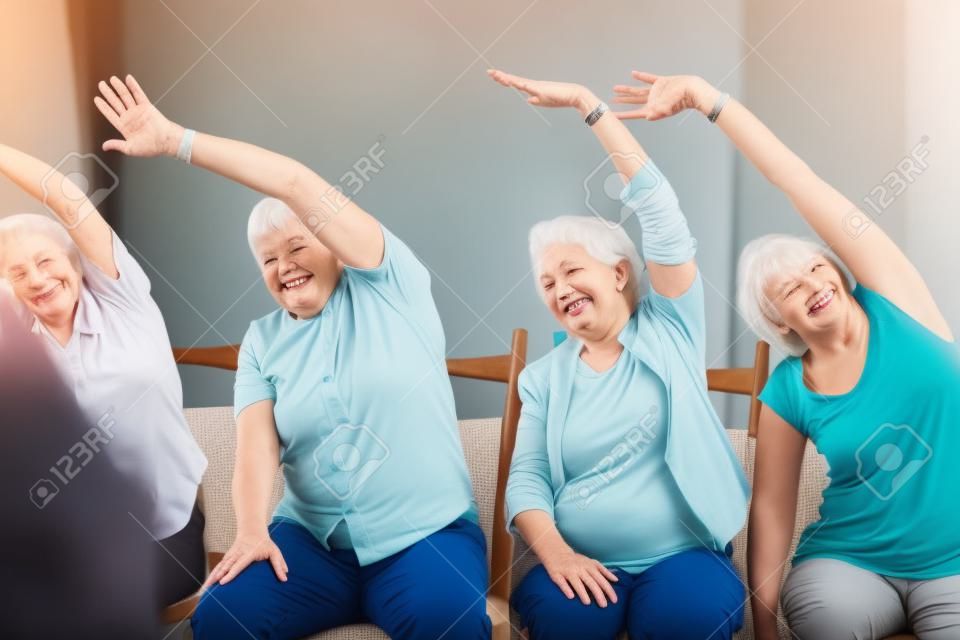Personas mayores que se extiende mientras que se sienta en sillas en la casa de retiro