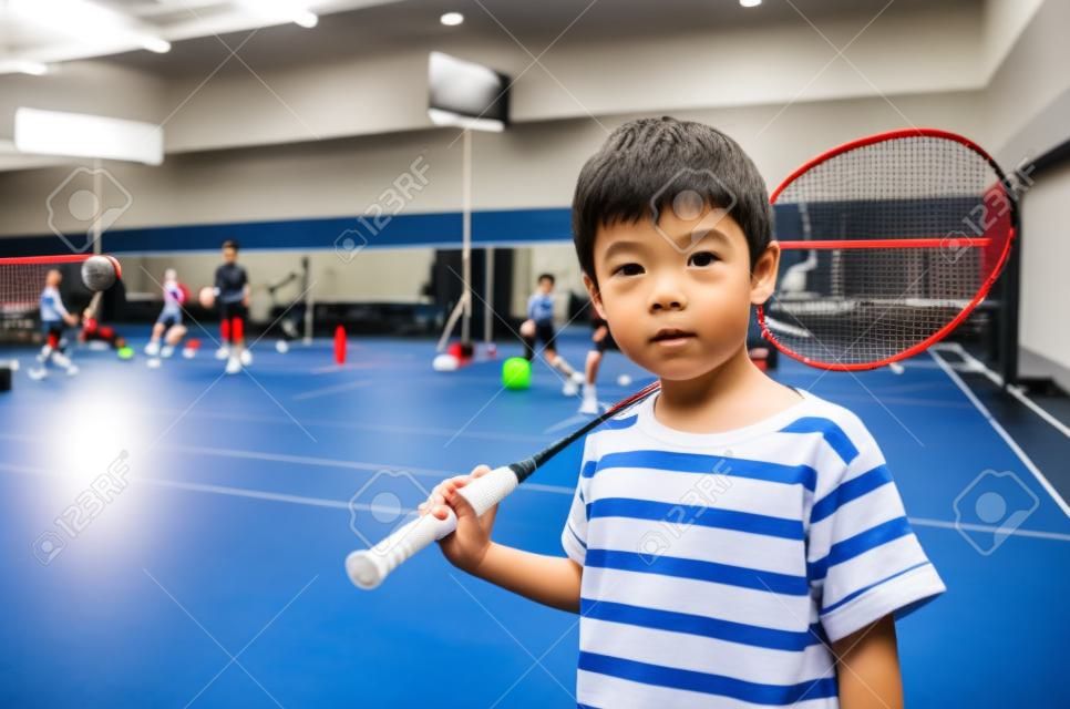小男孩服用羽毛球拍在培訓班在健身房