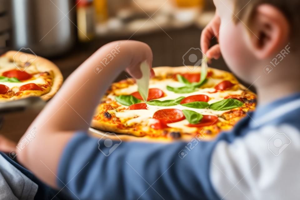 Kleine jongen koken pizza zelfgemaakt in de keuken thuis