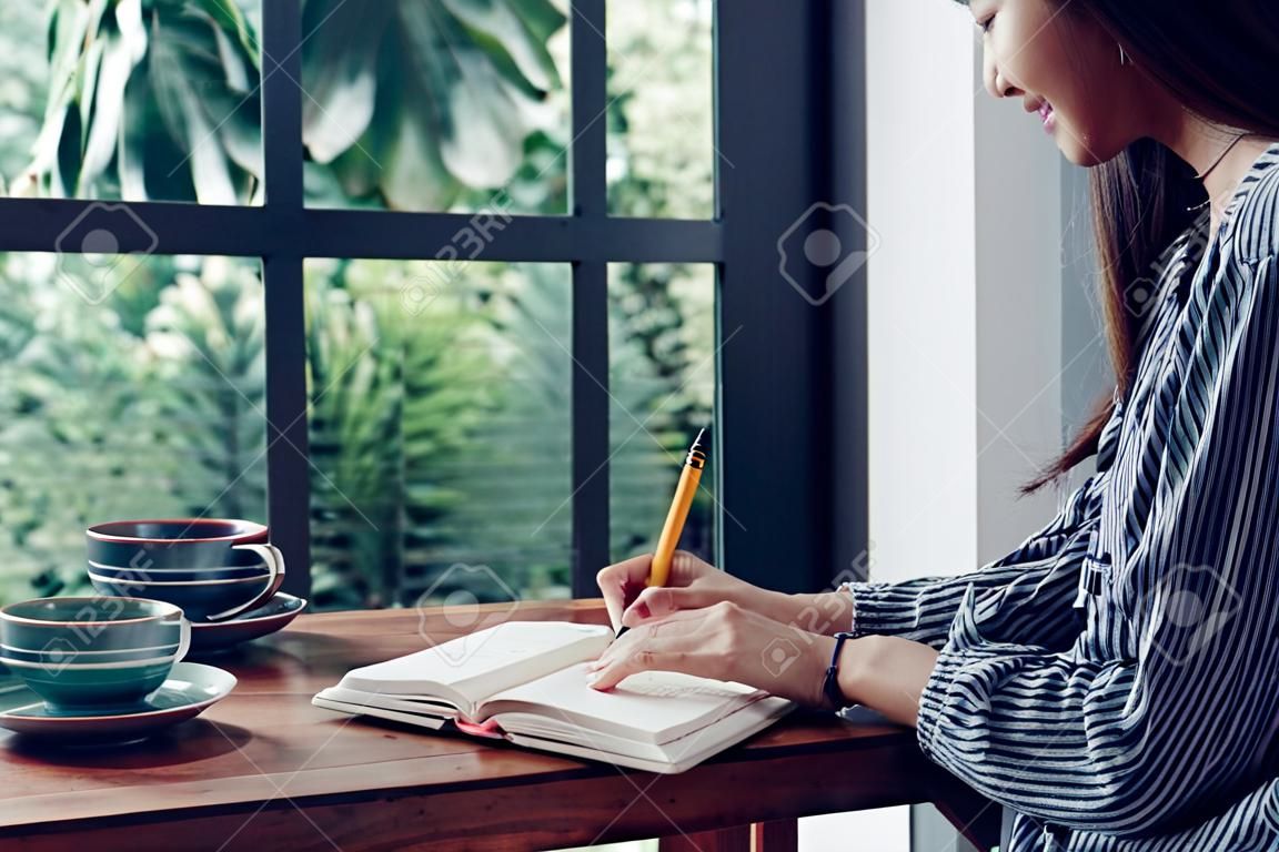 Azjatka pisze listę rzeczy do zrobienia na białym notatniku, słuchając muzyki w domu w czasie kwarantanny