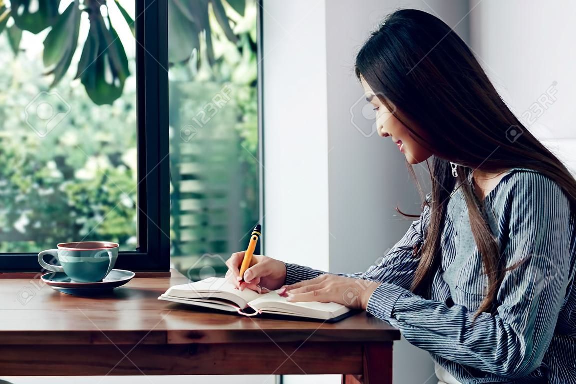 Azjatka pisze listę rzeczy do zrobienia na białym notatniku, słuchając muzyki w domu w czasie kwarantanny