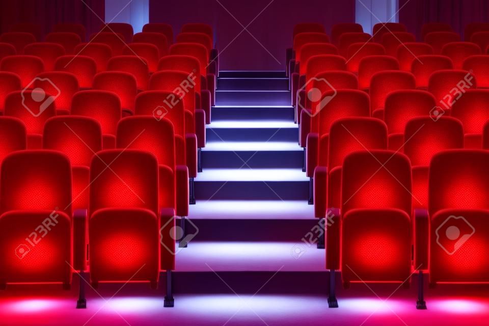 rangées de chaises rouges dans l'auditorium avec chemin d'escalier au milieu avec lumière