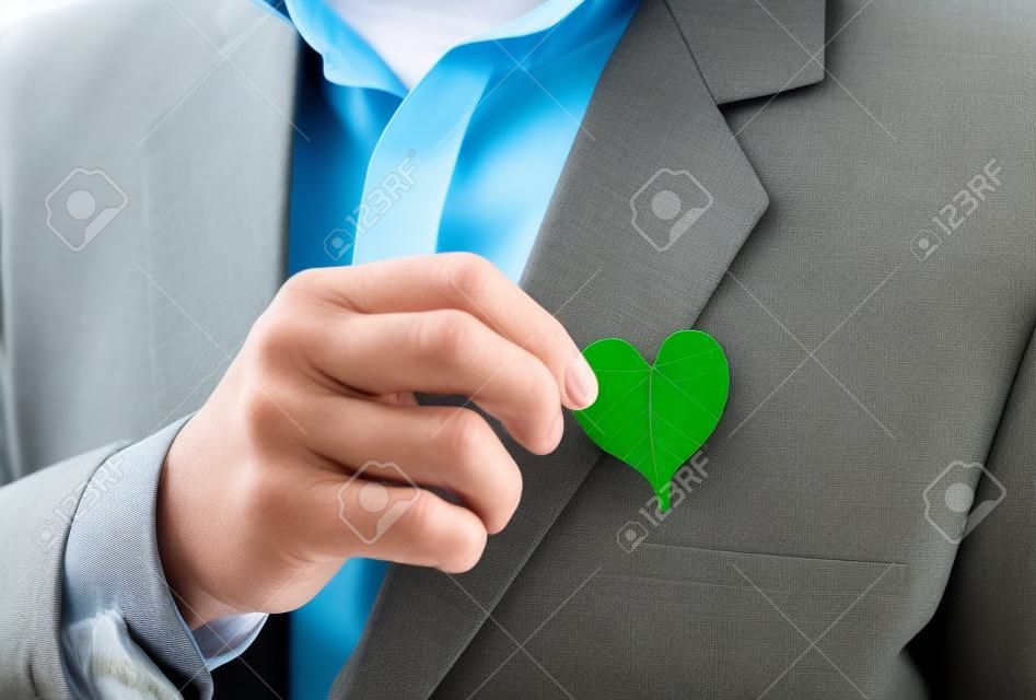 Businessman holding a green heart leaf / Business with corporate social responsibility and environmental concern
