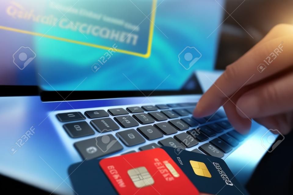 Carte di credito Furto Concept. Hacker con carte di credito sul suo computer portatile li utilizzano per non autorizzato Shopping. pagamenti non autorizzati