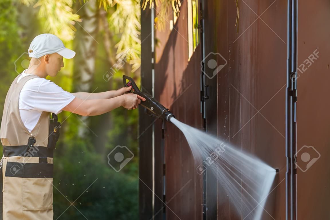 Puertas de garaje del agua de limpieza. Las paredes del garaje y la puerta Potente alta presión lavado con agua. Trabajador caucásico limpieza Elementos de edificios.