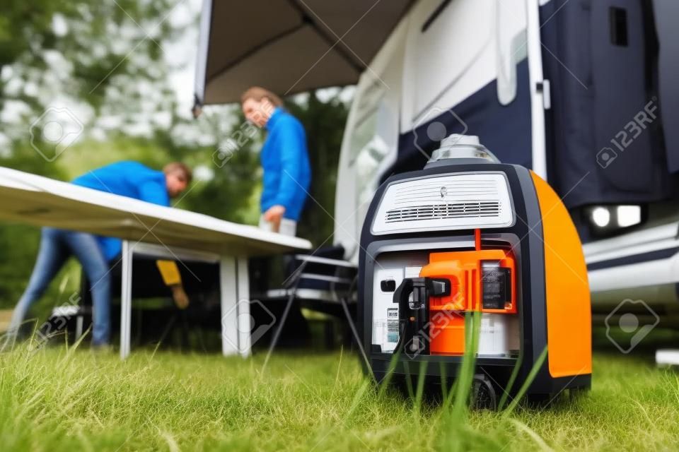 Modern Gasoline Powered Generator Running Next to Camper Van Recreational Vehicle. Powering RV Camping Pitch with Own Energy Source.