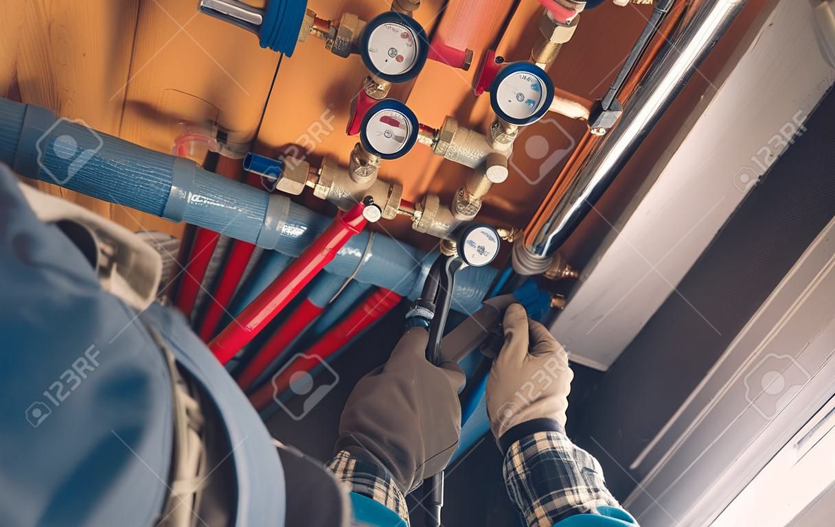 Vista aérea de fontanero con llave hidráulica realizando servicio y reparación de medidores de agua fría y caliente. tema de suministro de agua residencial.