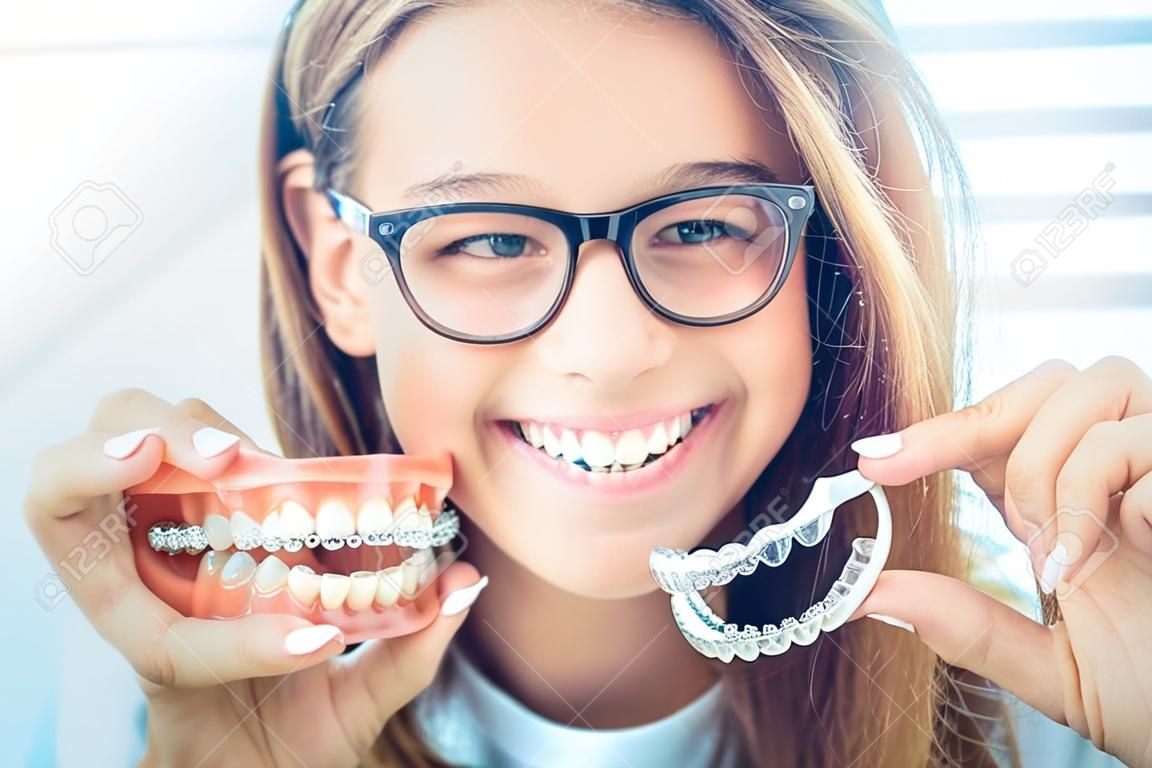 Niewidoczne aparaty dentystyczne lub silikonowy trener w rękach młodej uśmiechniętej dziewczyny. koncepcja ortodontyczna - invisalign.