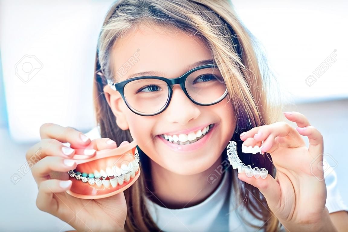 Tandheelkundige onzichtbare beugel of siliconen trainer in de handen van een jong glimlachend meisje. Orthodontisch concept - Invisalign.