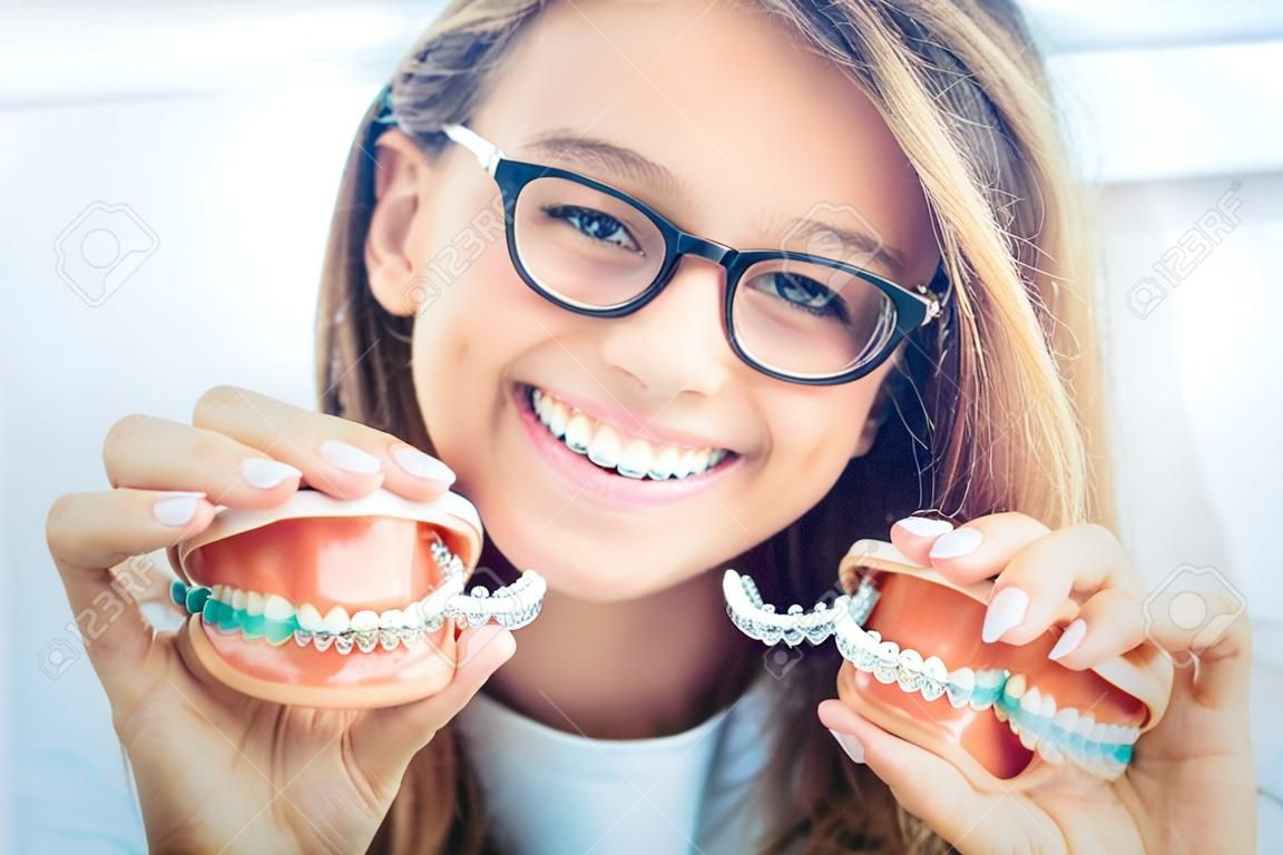 Unsichtbare Zahnspangen oder Silikontrainer in den Händen eines jungen lächelnden Mädchens. Kieferorthopädisches Konzept - Invisalign.