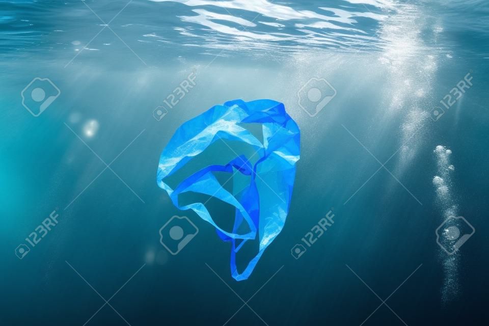 Unterwasserverschmutzung: - Eine weggeworfene Plastiktüte, die in einem tropischen Ozean mit blauem Wasser treibt