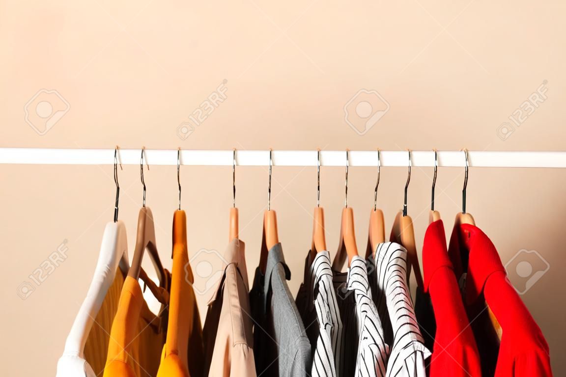 ropa de moda en perchas en un estante de armario sobre un fondo de color.