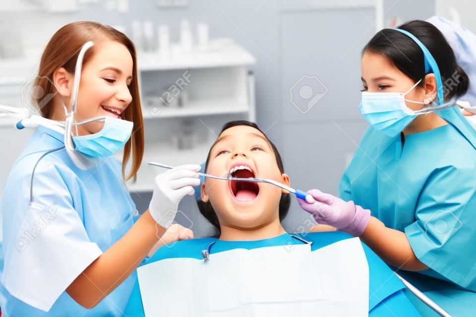 Two little dentist and dental assistant with a examining mouth of an adult patient. They are very young girls and the patient is a man. This is a funny  and surreal situation.