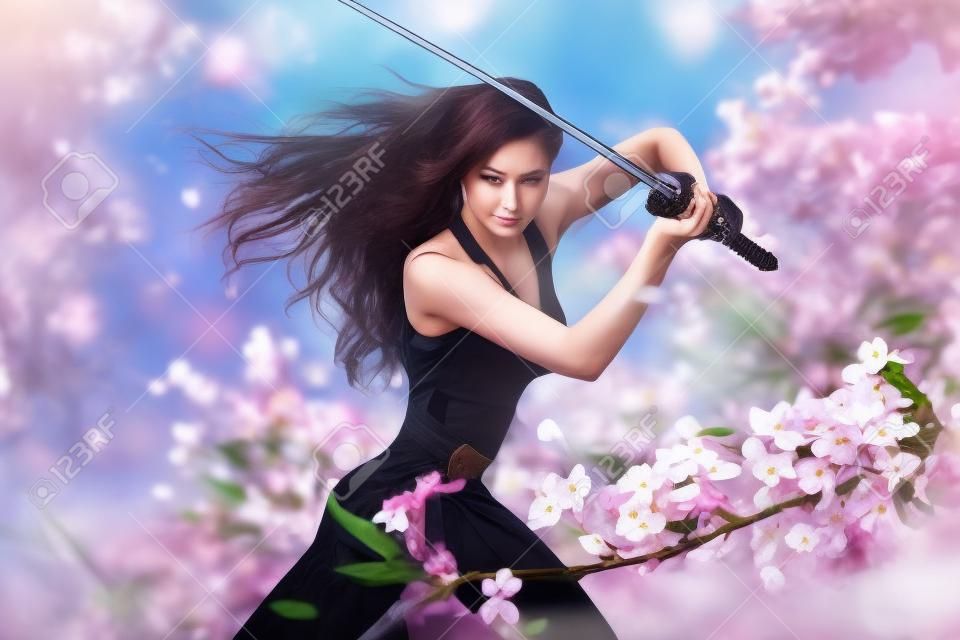 Prachtige Brunette met katana zwaard in de lente florale omgeving