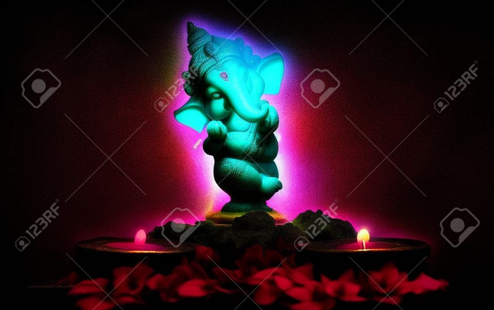 bella fotografia della statua di ganpati con due lampade luminose e fiori sullo sfondo nero. concetto di induismo