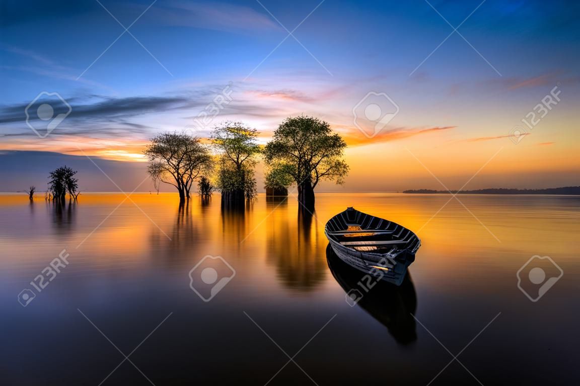어부의 보트와 아름 다운 아침 빛 호수에 나무.
