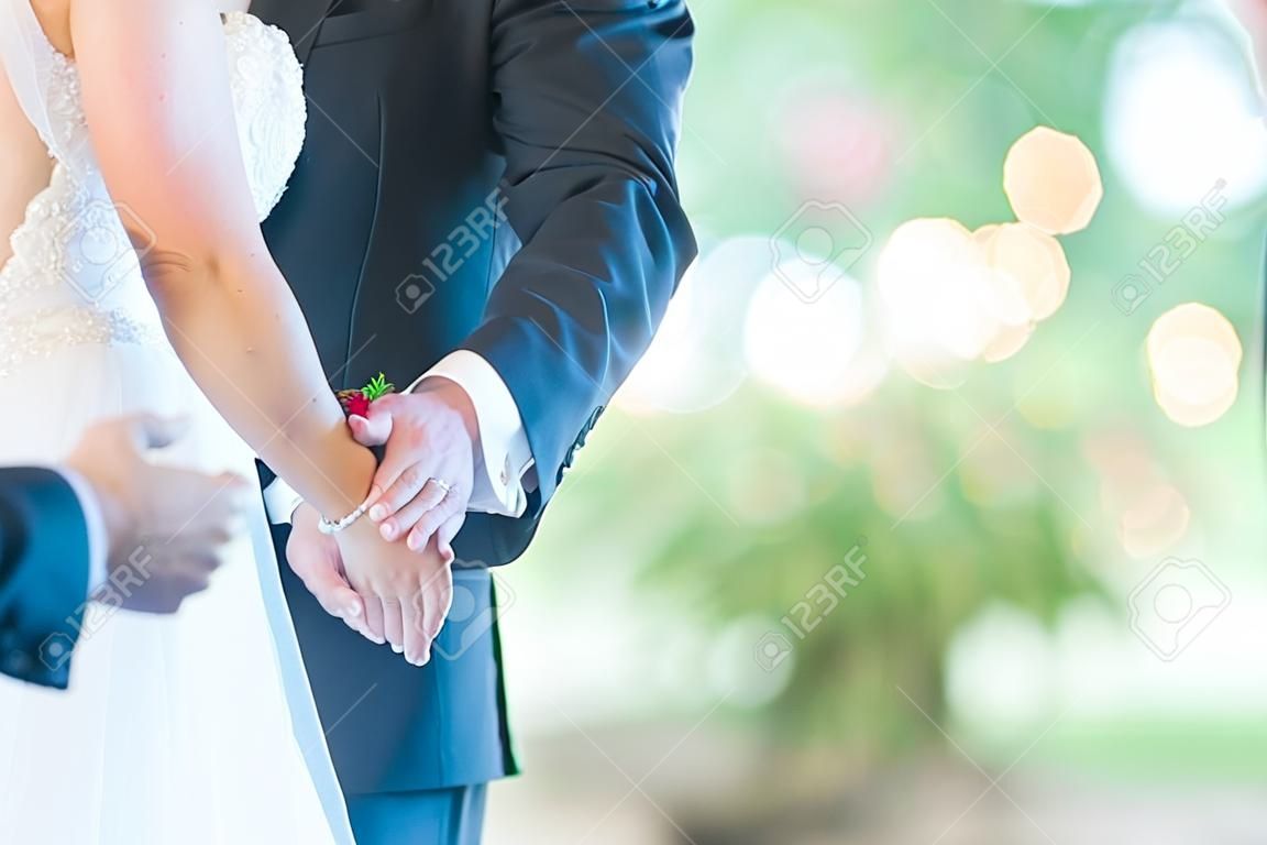 Eine flache Fokusaufnahme der Braut und des Bräutigams, die sich beim Tanzen an den Händen halten