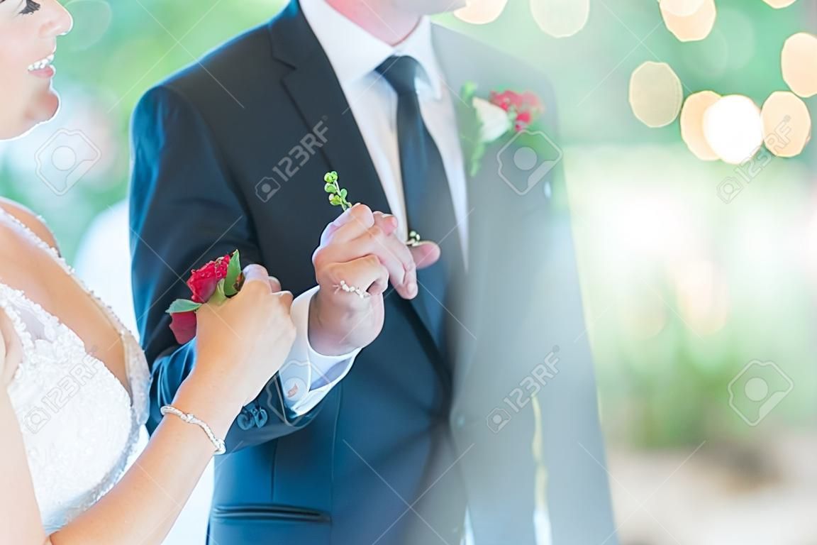 A shallow focus shot of the bride and the groom holding each others' hands while dancing