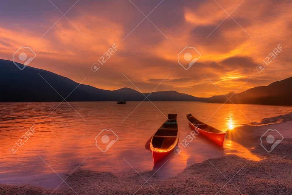 Two canoes at the lakeshore with a beautiful sunrise in the horizon