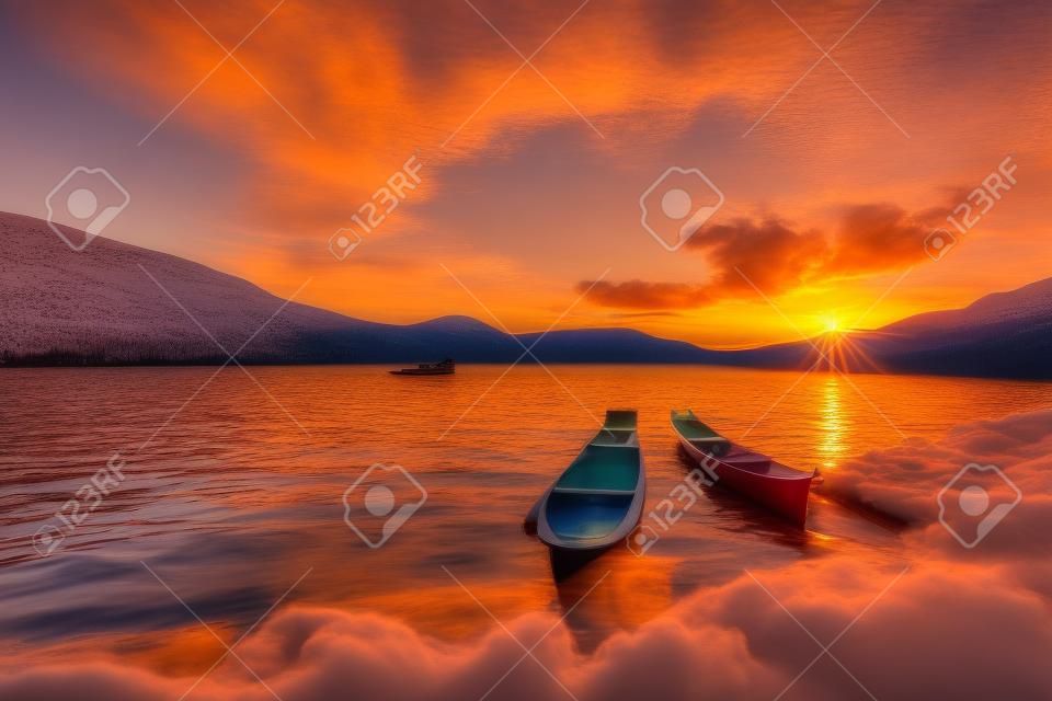 Dwa kajaki na brzegu jeziora z pięknym wschodem słońca na horyzoncie