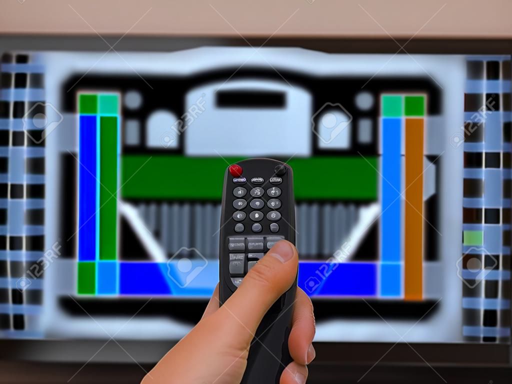 Remote control in a hand against a TV with a test screen