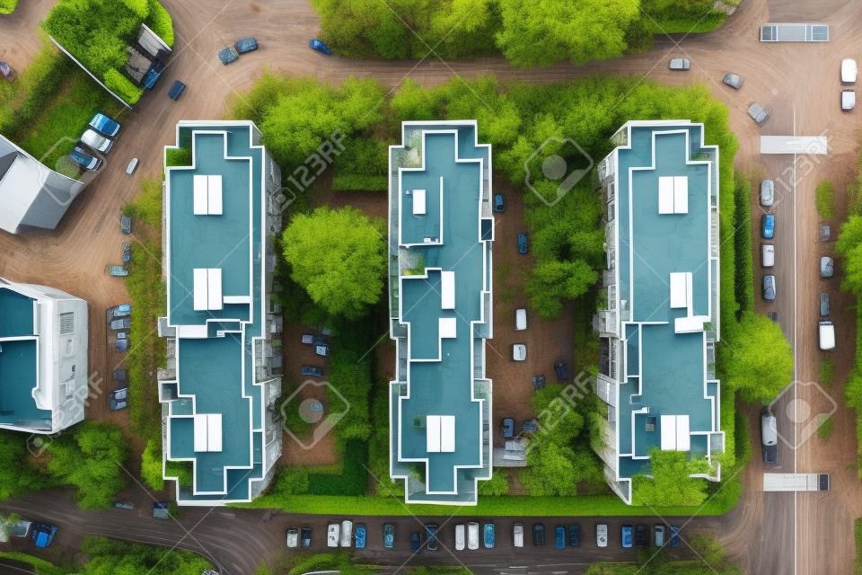 A top view of three identical apartment buildings with trees and cars on the street
