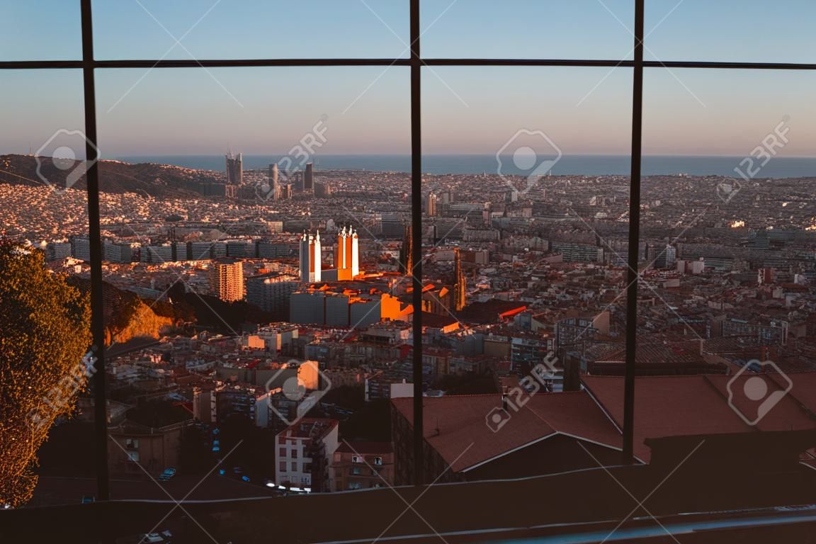 A scenic cityscape of Barcelona through a metal lattice window, view from Bunkers del Carmel (Colina de la Rovira)