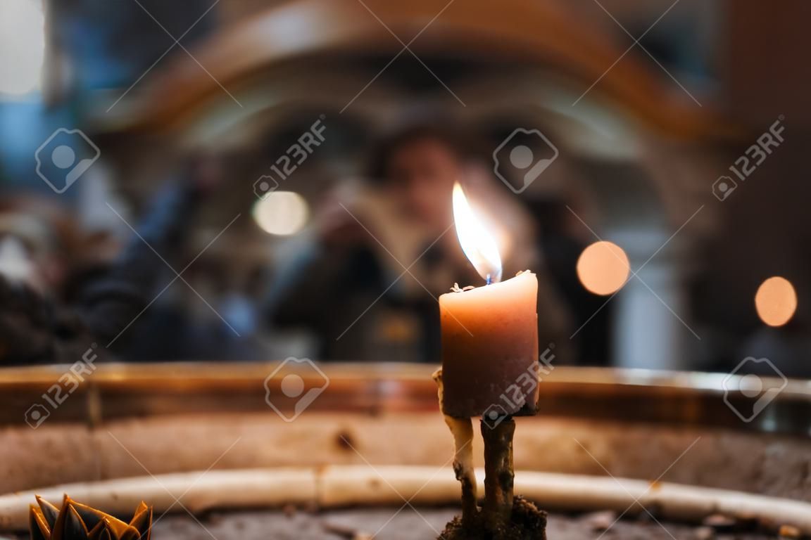 A selective closeup of a burning candle in a church