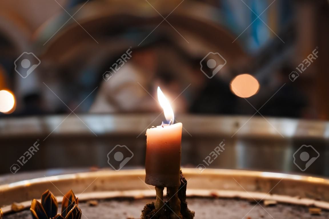 A selective closeup of a burning candle in a church