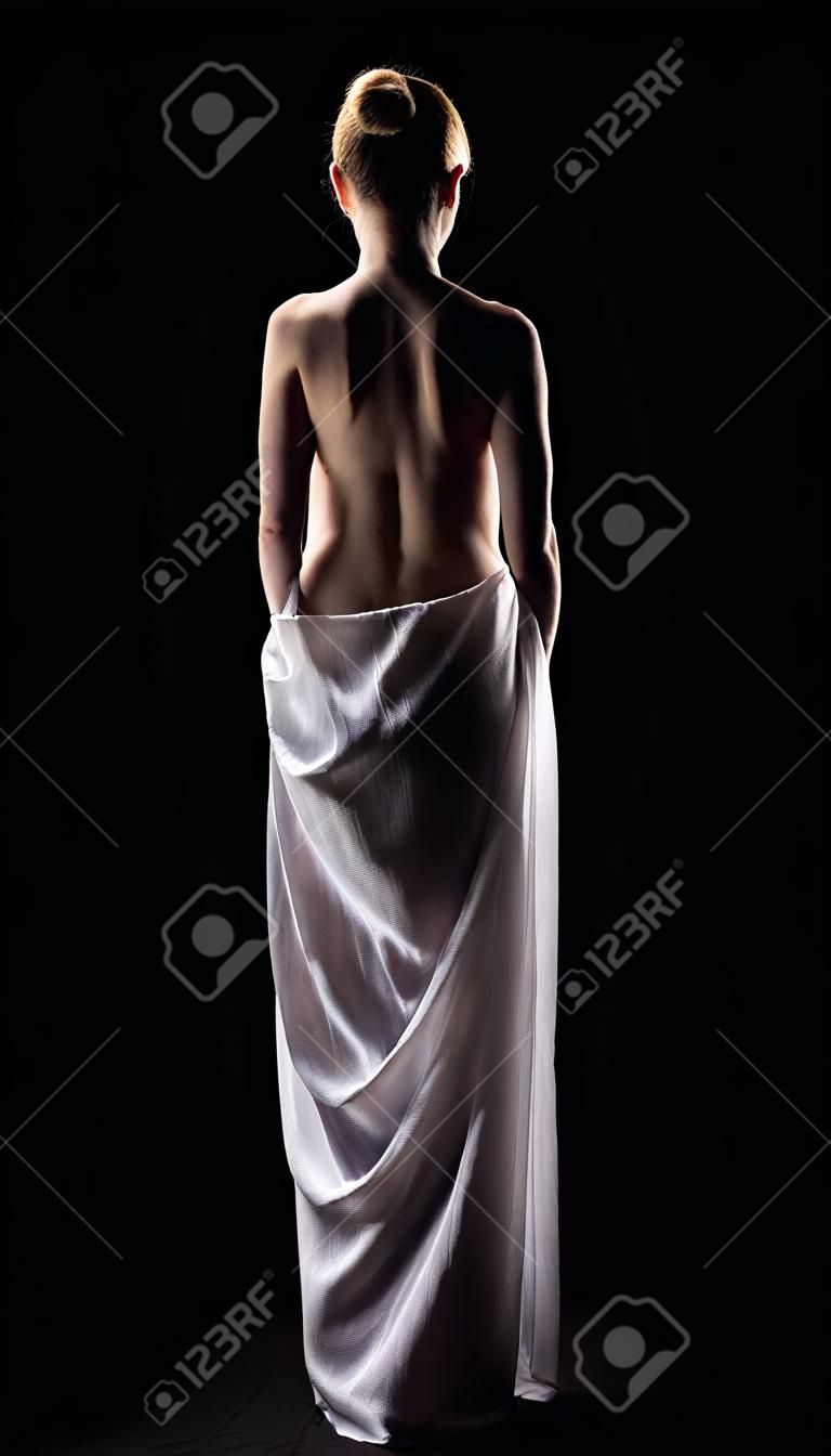 Beautiful woman posing like statue in dark with cloth